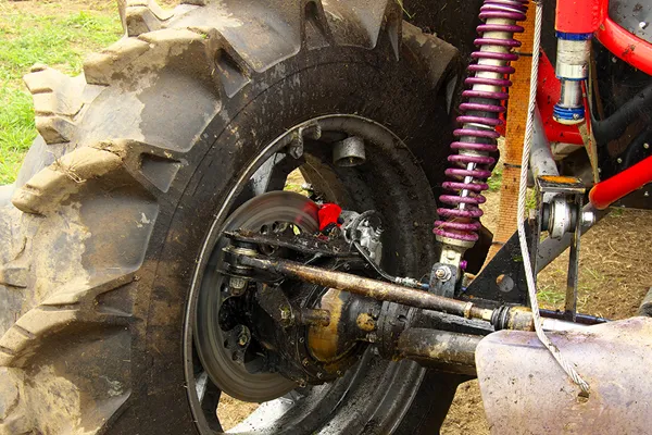 Shock absorber under severe operating conditions with heavy load Off-road vehicle with heavy load driving on rough terrain showing suspension compression