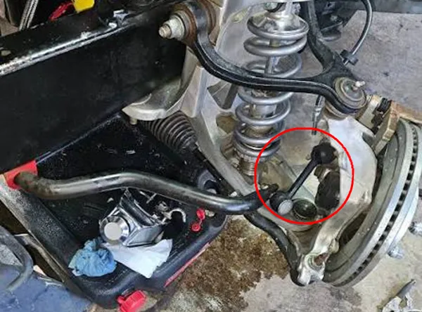 Mechanic wiggling sway bar link to check for looseness and play check sway bar link play by wiggling